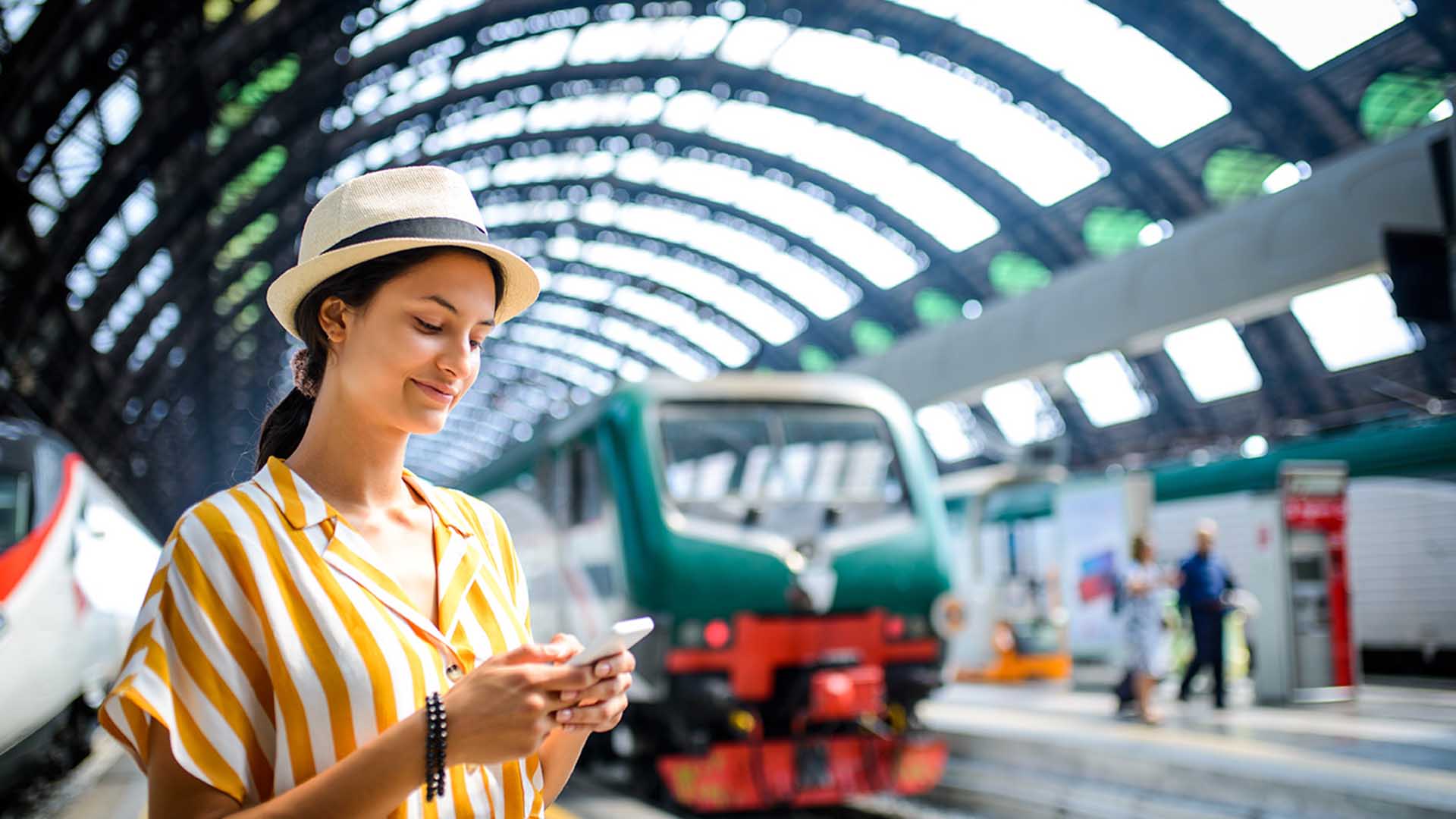 una donna in stazione con un cappello che guarda un telefono