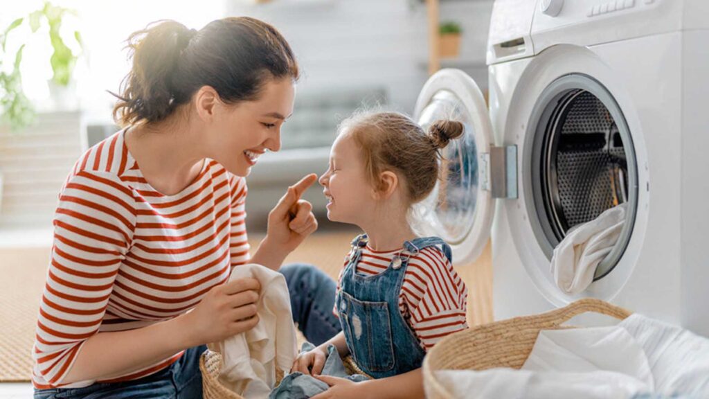 una donna e una bambina seduti davanti a una lavatrice