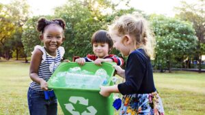 un gruppo di bambini con in mano un bidone verde per la raccolta differenziata