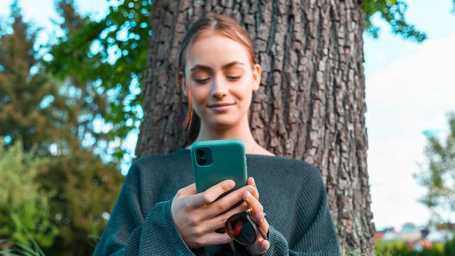 Eine Frau hält ein Telefon in der Hand und lächelt, während sie eine App nutzt