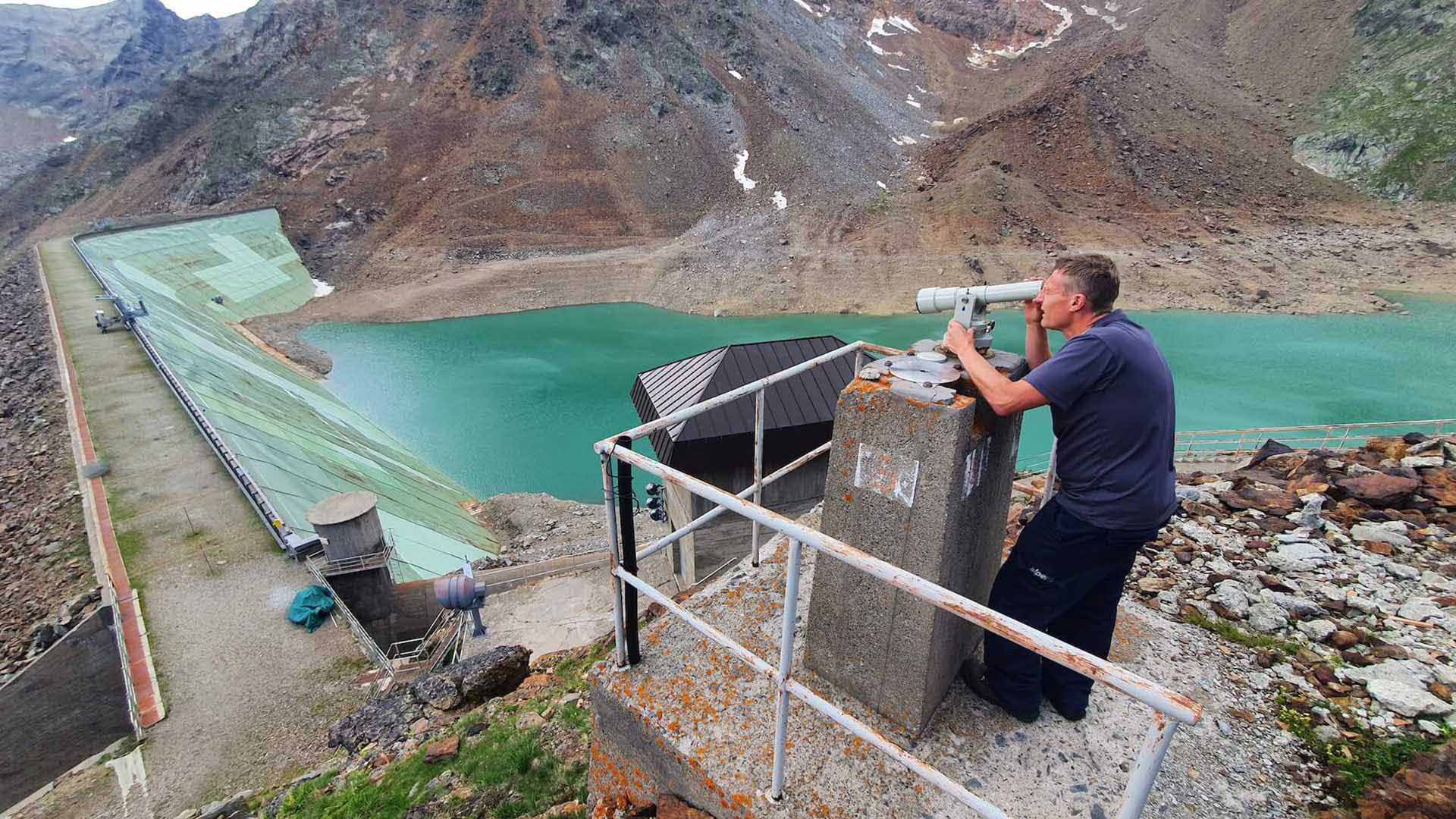 un uomo che controlla la diga attraverso un telescopio