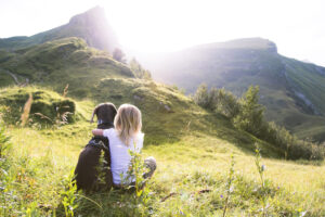 a girl sitting on a hill with a dog