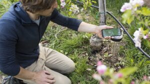 un uomo inginocchiato con in mano un telefono con l'app Smartland