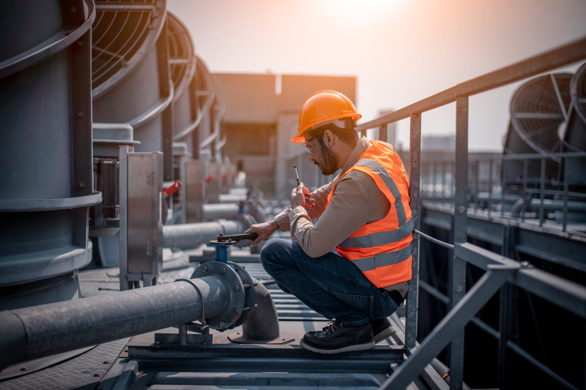 Ingegnere industriale impegnato nel controllo del condizionatore d'aria della torre di raffreddamento industriale, refrigeratore d'aria della torre di raffreddamento ad acqua HVAC di un grande edificio industriale per controllare il sistema dell'aria.