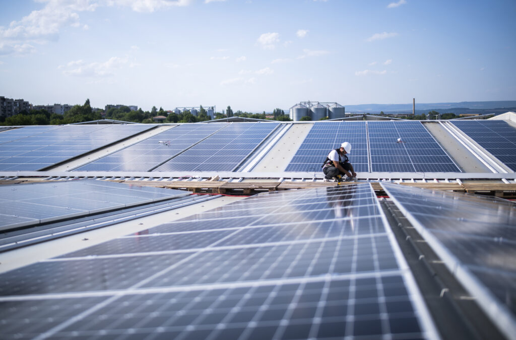 Ingegnere con casco protettivo che installa un sistema di pannelli fotovoltaici.