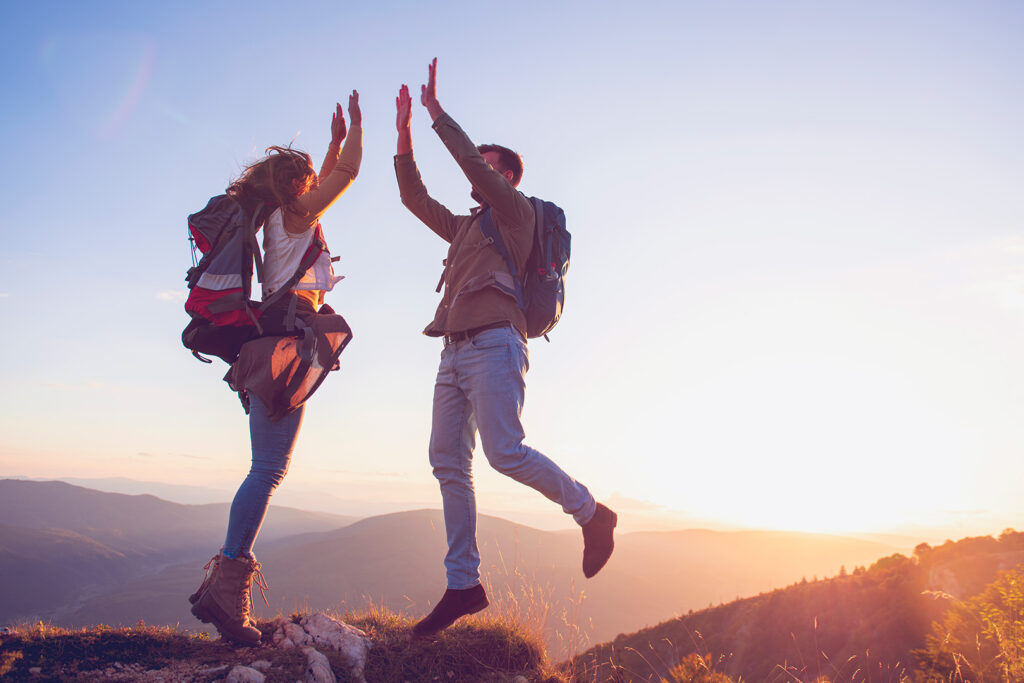 a man and woman high fiving on a mountain