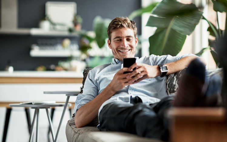 un uomo seduto su un divano che guarda il suo telefono