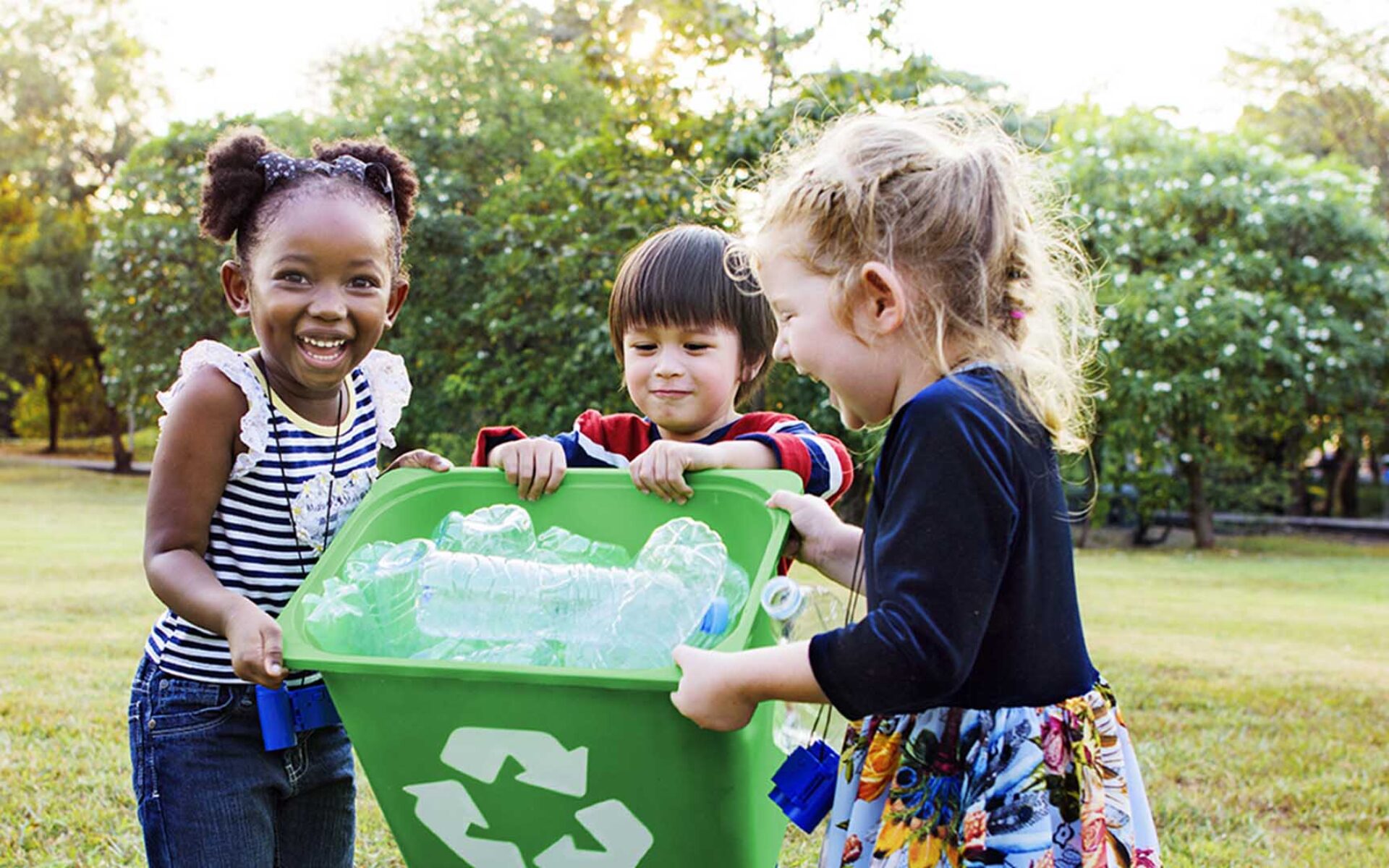 un gruppo di bambini con in mano un bidone verde per la raccolta differenziata